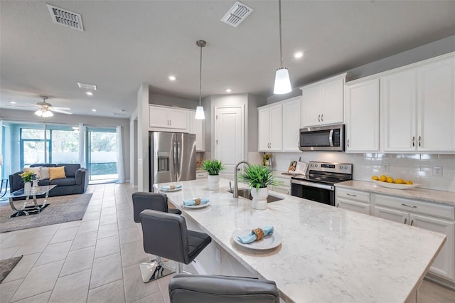 kitchen with an island with sink, visible vents, appliances with stainless steel finishes, and a sink