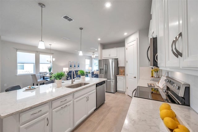 kitchen with stainless steel appliances, a sink, white cabinetry, tasteful backsplash, and decorative light fixtures