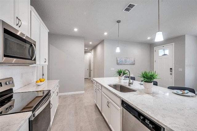 kitchen with stainless steel appliances, visible vents, white cabinets, a sink, and light stone countertops