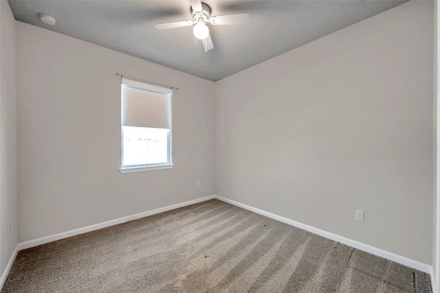 carpeted empty room with a ceiling fan and baseboards