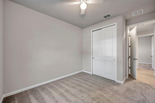 unfurnished bedroom featuring light colored carpet, ceiling fan, and a closet