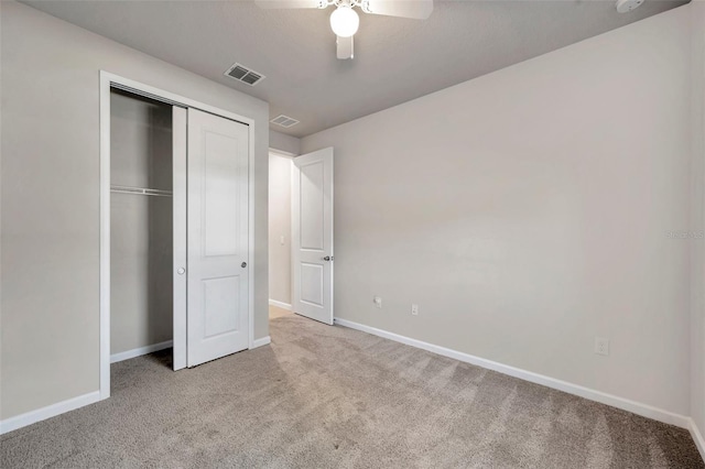 unfurnished bedroom with ceiling fan, light colored carpet, and a closet