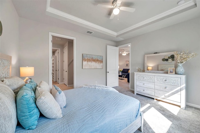 bedroom with carpet floors, ceiling fan, and a tray ceiling