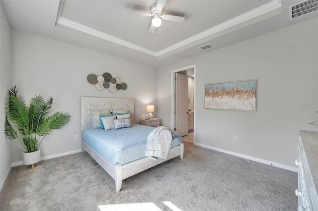 bedroom with carpet floors, a tray ceiling, and visible vents