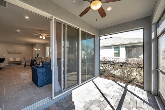 sunroom / solarium featuring ceiling fan with notable chandelier