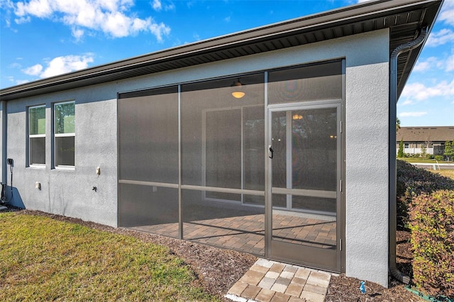 view of side of property featuring a sunroom and stucco siding