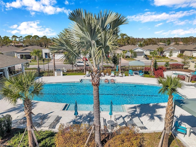 community pool with a patio area, fence, and a residential view