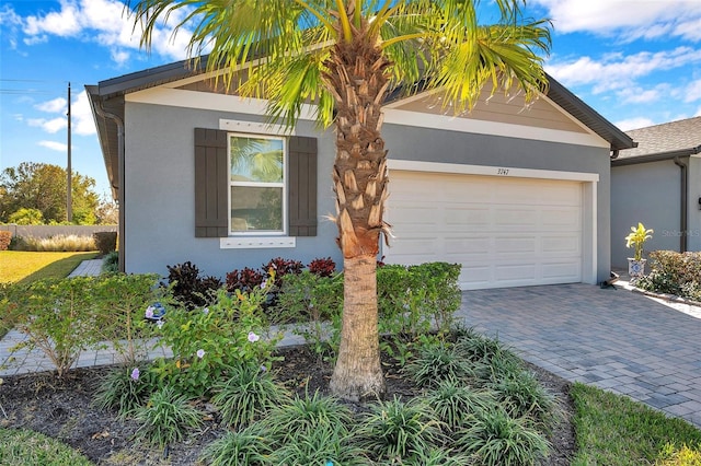 view of front of home with a garage, decorative driveway, and stucco siding