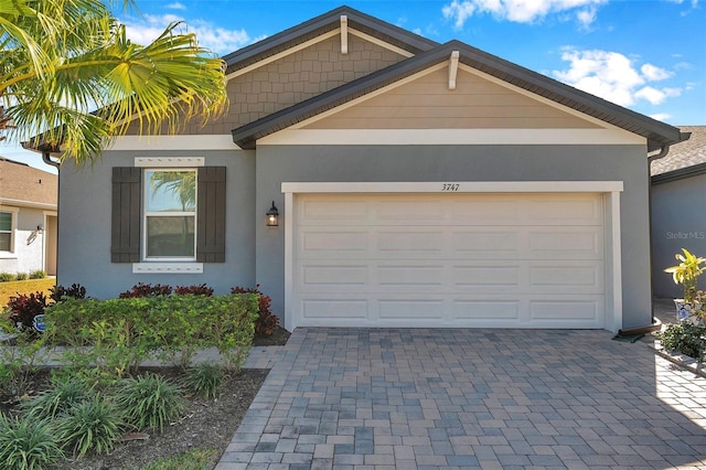 view of front of home featuring an attached garage, decorative driveway, and stucco siding