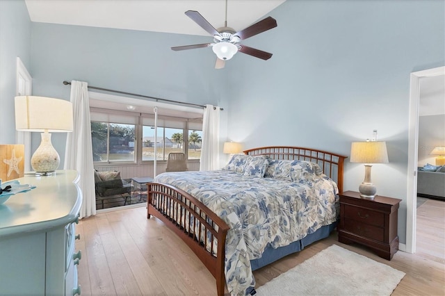 bedroom with a towering ceiling, ceiling fan, and light hardwood / wood-style flooring