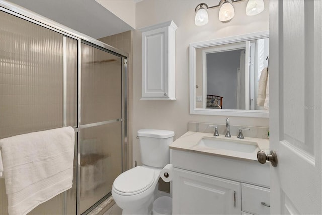 bathroom with vanity, a shower with door, and toilet