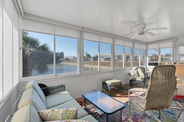 sunroom with ceiling fan and a water view