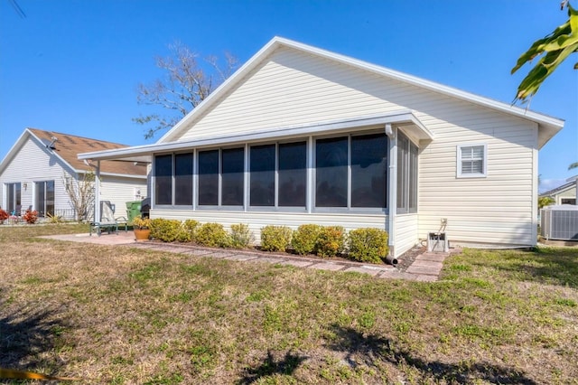 back of property with a sunroom, a lawn, central air condition unit, and a patio area