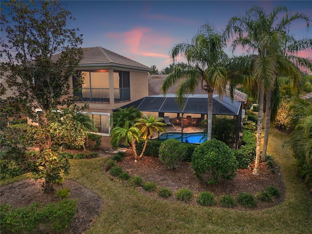 back house at dusk featuring a lanai