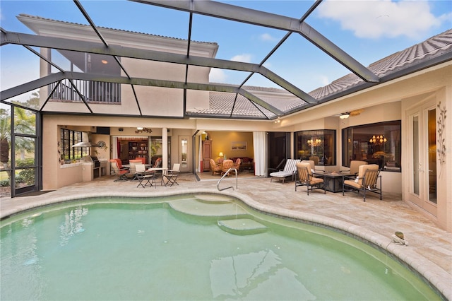 view of swimming pool featuring ceiling fan, an outdoor fire pit, a patio area, and glass enclosure