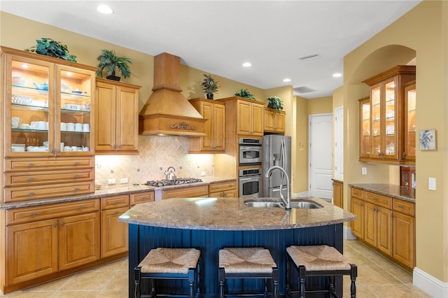 kitchen featuring premium range hood, a kitchen island with sink, and a breakfast bar