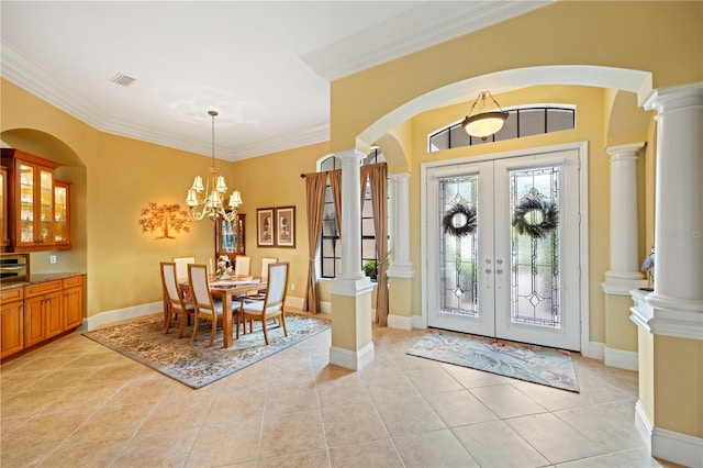 foyer entrance featuring light tile patterned floors, ornamental molding, decorative columns, and french doors