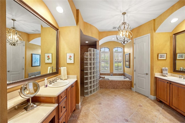 bathroom featuring tile patterned floors, vanity, a chandelier, and tiled tub