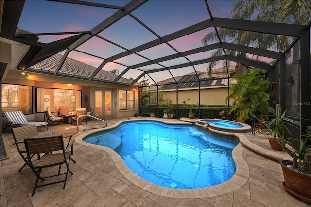 pool at dusk with an in ground hot tub, a lanai, and a patio area