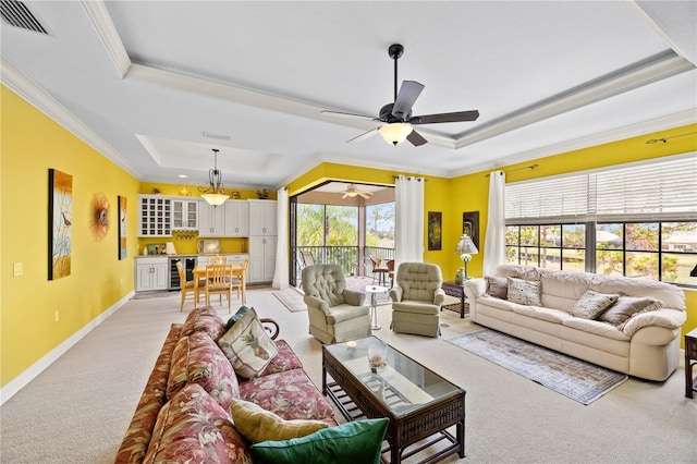 living room with wine cooler, ornamental molding, and a raised ceiling