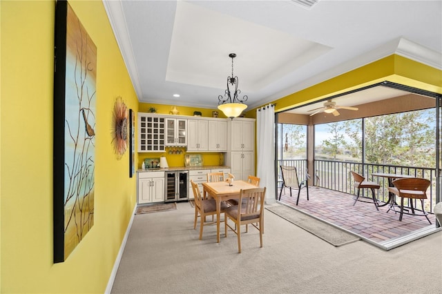 carpeted dining room with crown molding, beverage cooler, a raised ceiling, and bar area