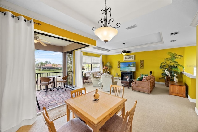 dining area featuring a raised ceiling, carpet floors, and ceiling fan