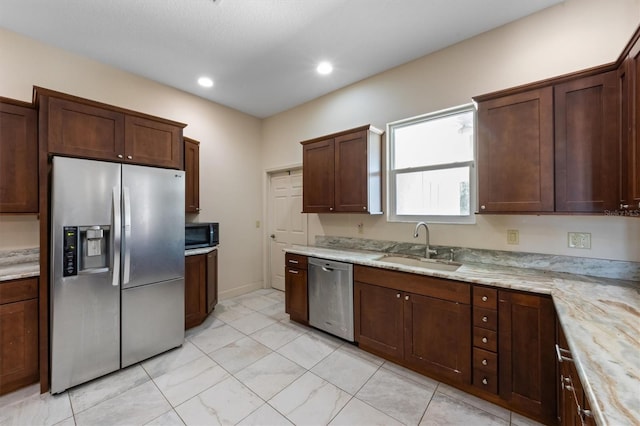 kitchen featuring light stone counters, appliances with stainless steel finishes, sink, and dark brown cabinets