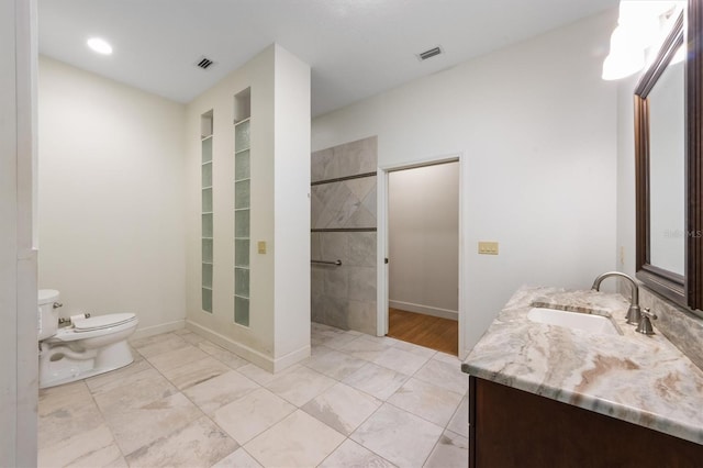 bathroom with vanity, a tile shower, and toilet