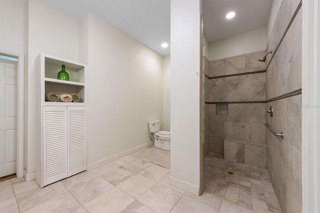 bathroom with a tile shower and toilet