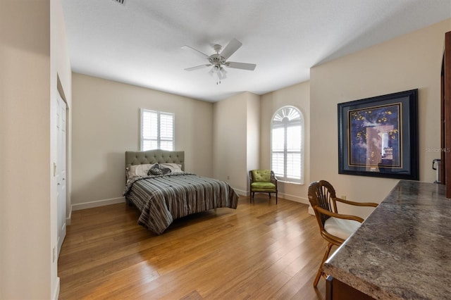 bedroom with ceiling fan, wood-type flooring, and multiple windows