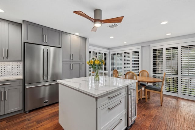 kitchen with gray cabinets, a kitchen island, wine cooler, light stone counters, and high end fridge