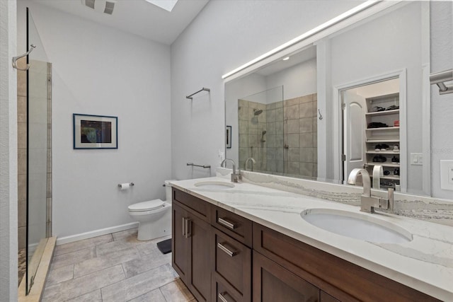 bathroom featuring a skylight, vanity, toilet, and a shower with shower door