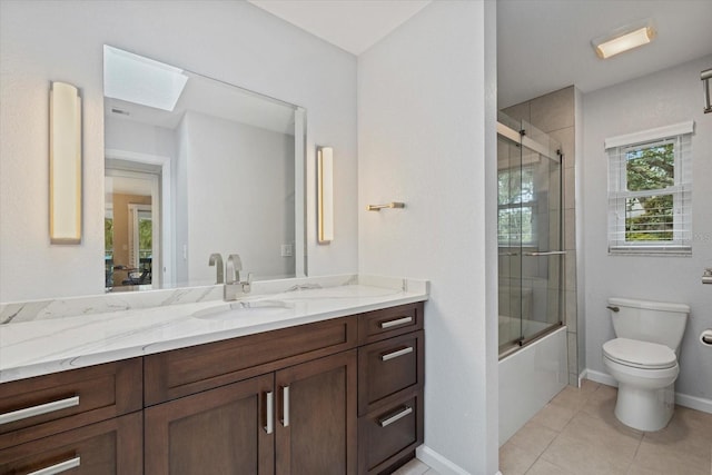 full bathroom featuring bath / shower combo with glass door, a skylight, tile patterned flooring, vanity, and toilet