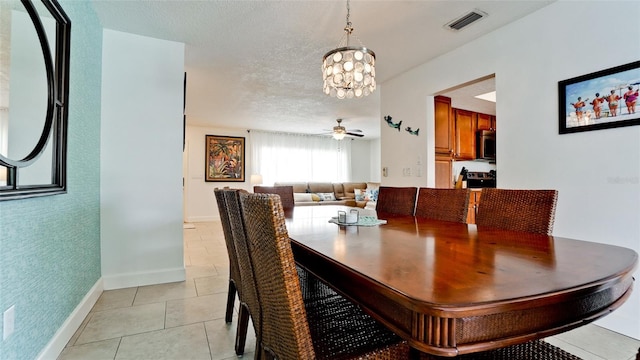 tiled dining room featuring ceiling fan with notable chandelier and a textured ceiling