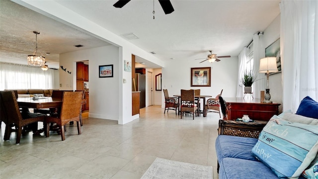 tiled living room with ceiling fan with notable chandelier