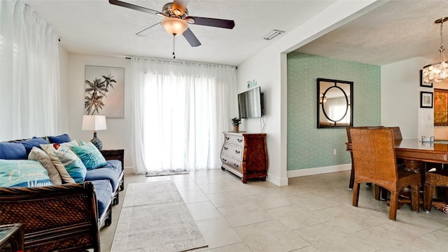 living room with light tile patterned flooring, ceiling fan, and a textured ceiling