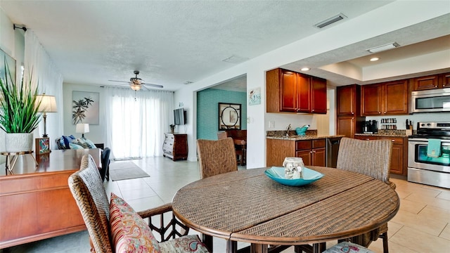 dining space featuring ceiling fan, a textured ceiling, and light tile patterned flooring