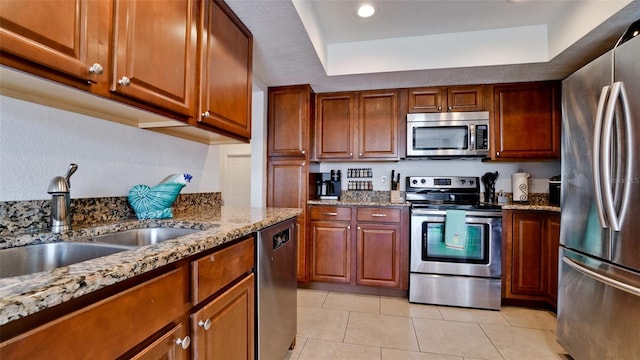 kitchen with light stone countertops, light tile patterned floors, stainless steel appliances, and sink