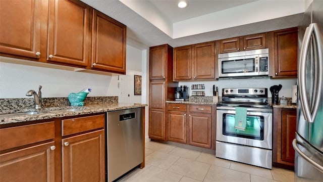 kitchen with light stone counters, sink, stainless steel appliances, and light tile patterned flooring