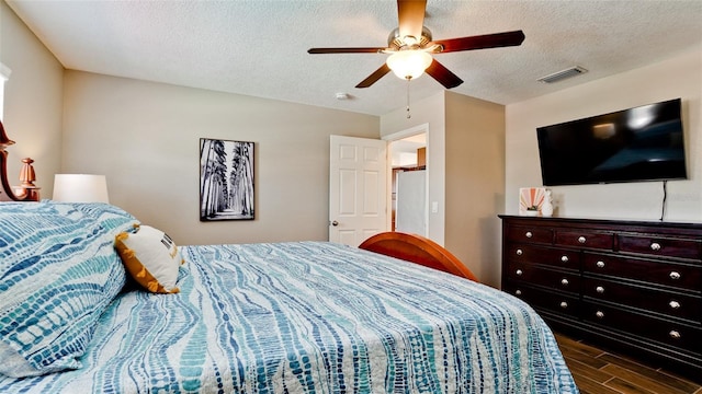 bedroom with dark wood-type flooring, ceiling fan, and a textured ceiling