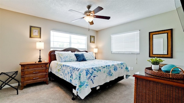 bedroom with ceiling fan, light carpet, and a textured ceiling