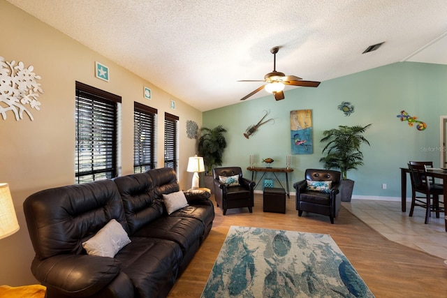 living room featuring lofted ceiling, a textured ceiling, and light hardwood / wood-style floors