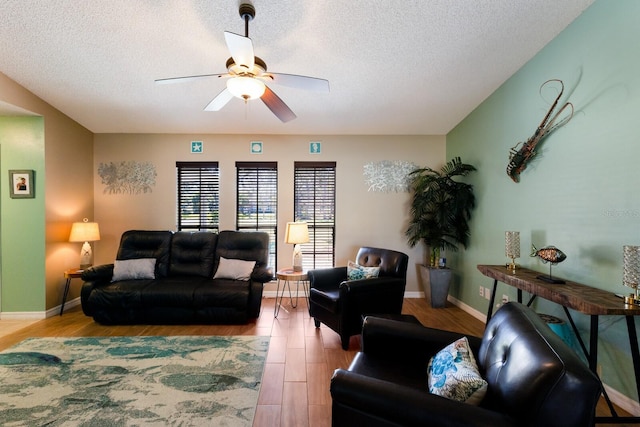 living room featuring ceiling fan, a textured ceiling, and light wood-type flooring