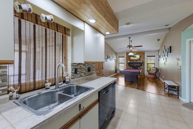 kitchen with tile counters, dishwasher, sink, and white cabinets