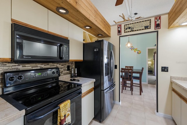 kitchen with pendant lighting, tasteful backsplash, white cabinets, light tile patterned floors, and black appliances