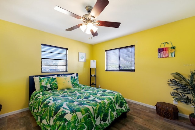 bedroom featuring ceiling fan, dark hardwood / wood-style floors, and multiple windows