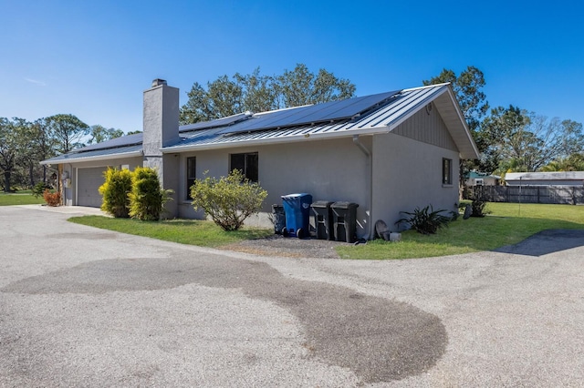 view of side of home featuring a garage, a yard, and solar panels