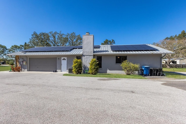 ranch-style house with a garage, cooling unit, and solar panels