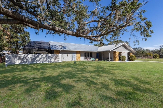 ranch-style house with metal roof and a front lawn