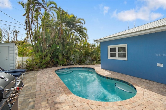 view of pool with area for grilling, a storage shed, and a patio area